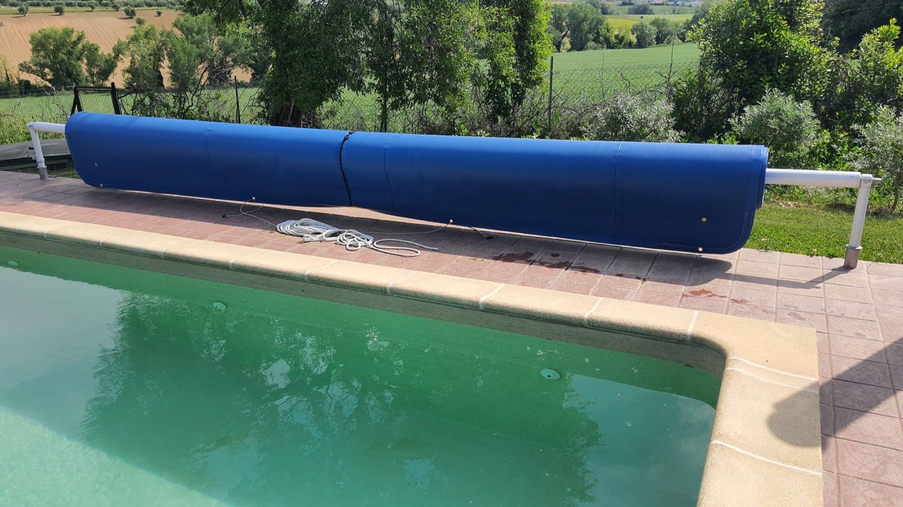 Coprirullo blu che protegge la copertura estiva arrotolata a bordo piscina